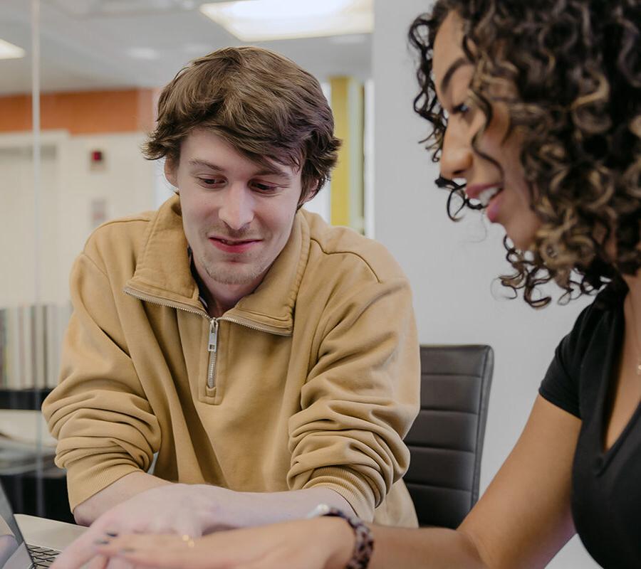 Two business administrat离子 students study together at a laptop