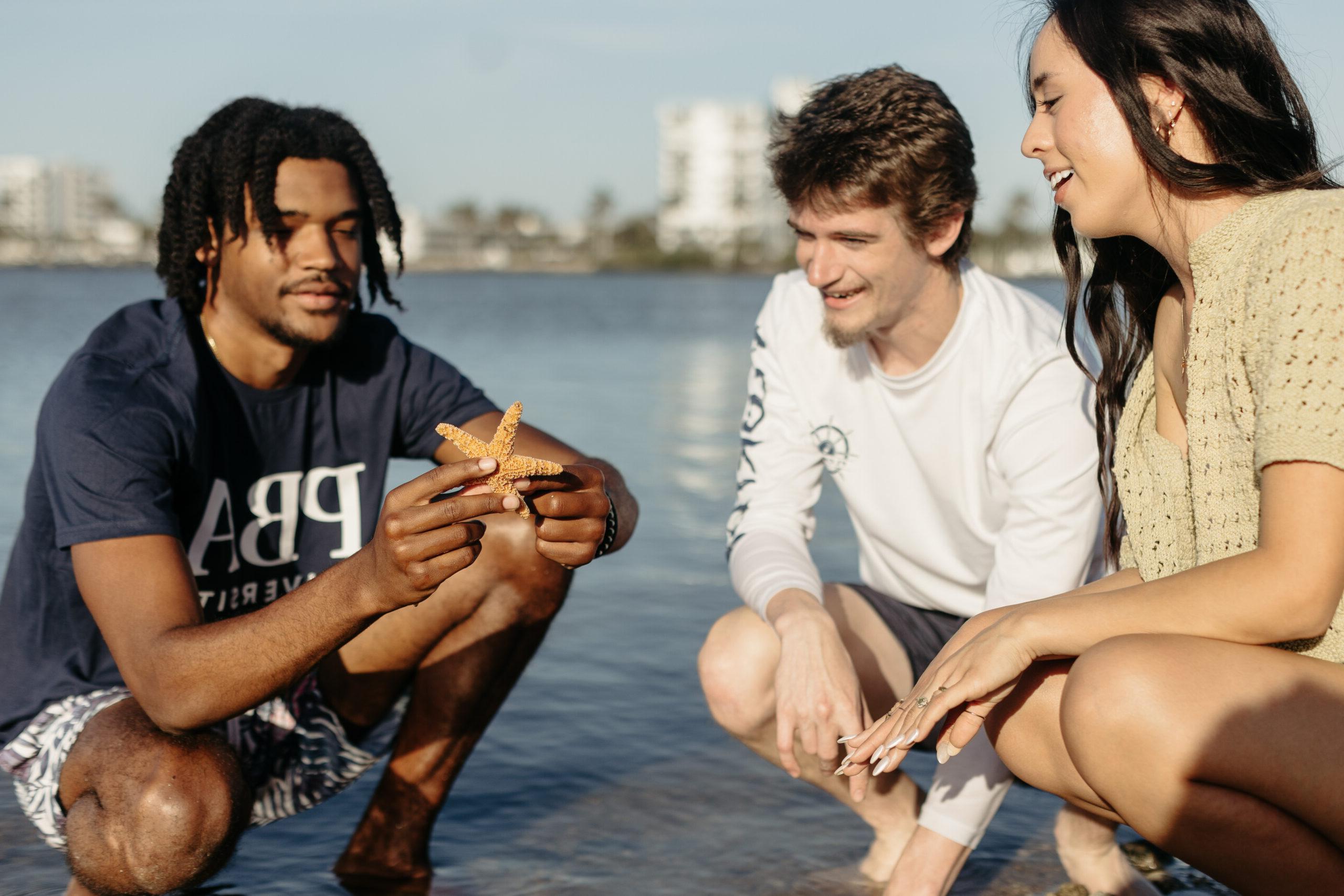 three PBA students looking at a starfish